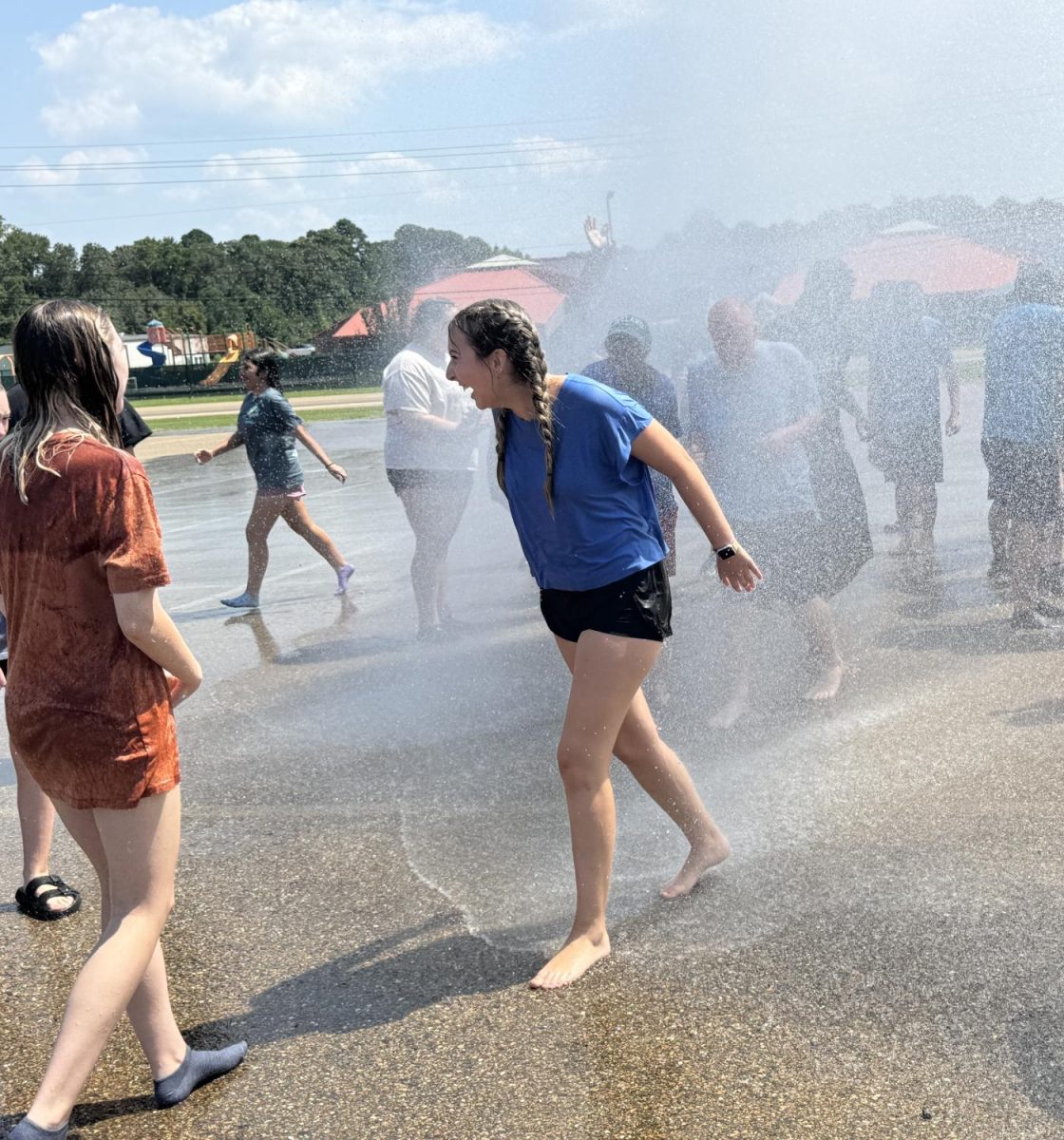 Junior Kadyn Roper screams with excitement as the fire truck sprays the band students to cool them down after a long summer practice. 