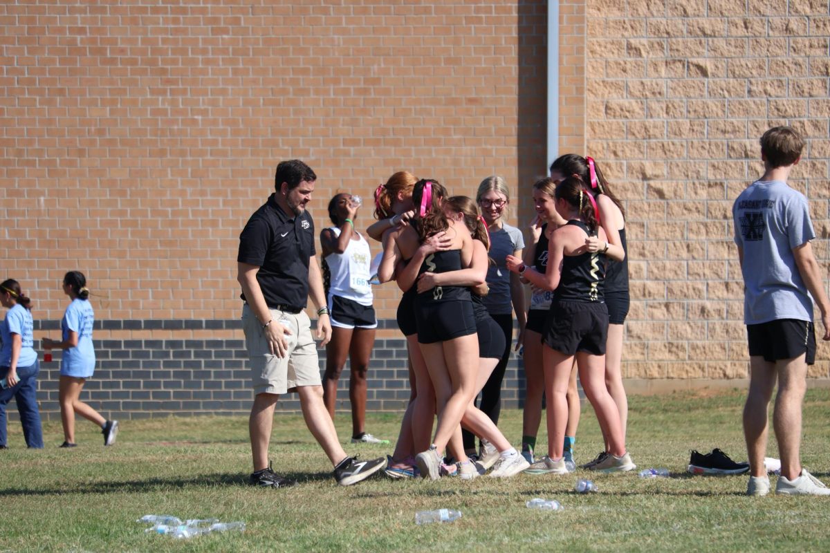 After finding out they advanced to regionals, the girls cross country team celebrates by the start line.